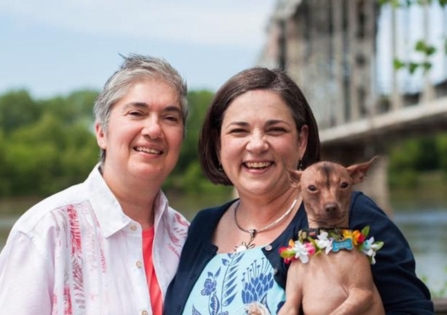 joe justus with her partner and chihuaha standing in front of a bridge